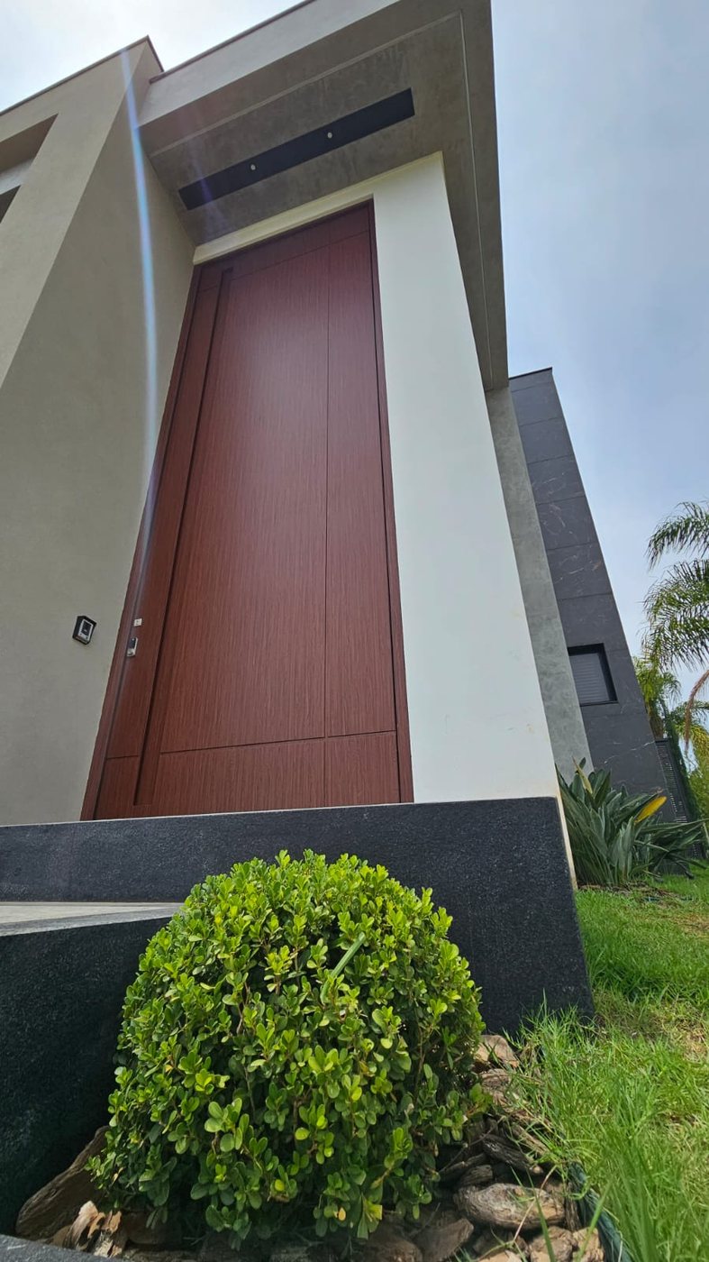 Residência com porta pivotante em ACM amadeirado